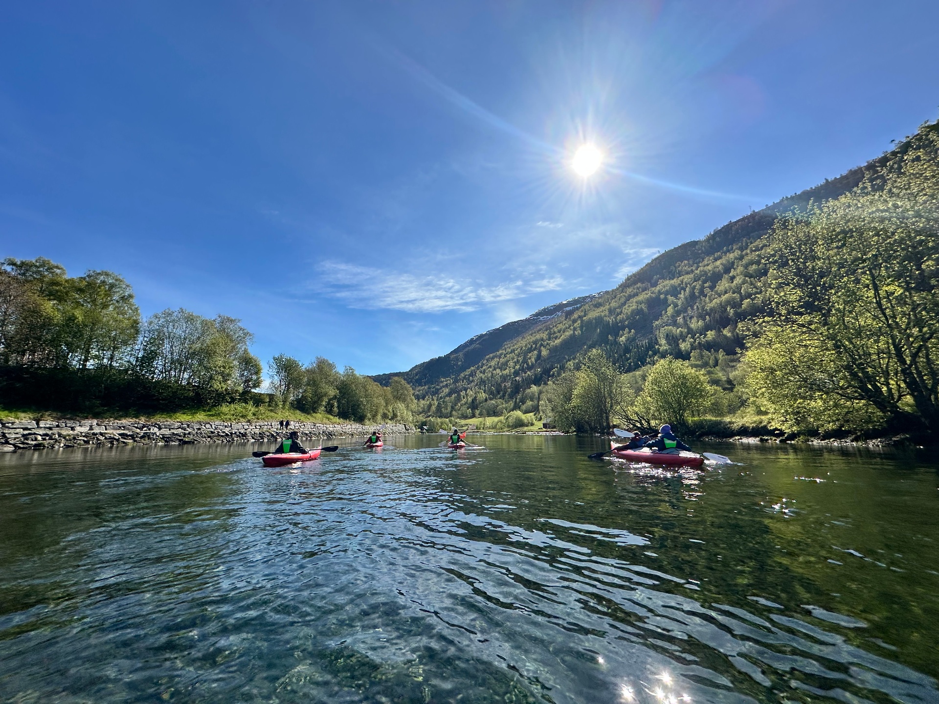 Kayakers paddling the calm river under sunshine